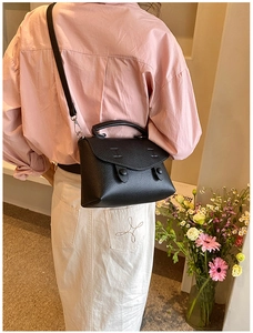 Primo piano della borsa a tracolla in pelle nera a grana litchi indossata da una modella