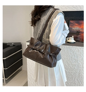 Détail du sac cabas en cuir marron foncé avec ceinture à œillets et boucle argent