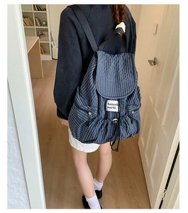Close-up of checkered nylon backpack with drawstring closure and vertical side zippers