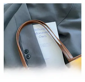Detailed view of brown leather handle stitching and edge paint on a yellow bucket bag