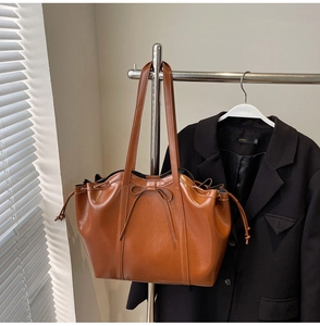 Detail view of brown faux leather tote bag with bow decoration and adjustable side drawstrings