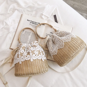 Handmade straw bucket bag with white lace floral trim and adjustable leather strap