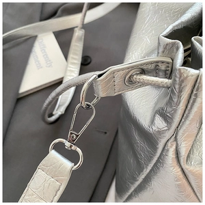 Détail du sac seau plissé argenté avec texture métallique et ferrures en argent poli
