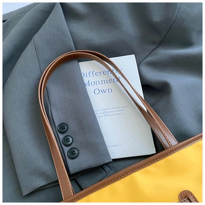 Detail of yellow contrast-stitch tote bag paired with a gray blazer for a stylish look