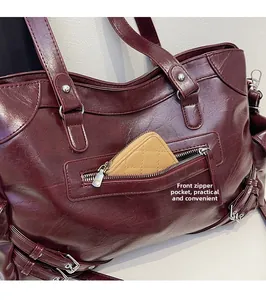 Detail of burgundy tote bag showing functional front zipper pocket with silver hardware