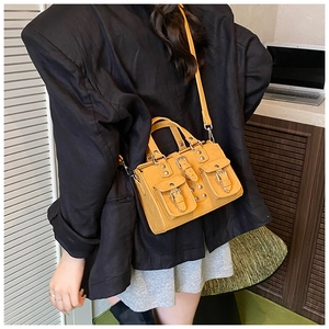 Ginger yellow leather crossbody bag with front flap pockets and rivet details on black suit