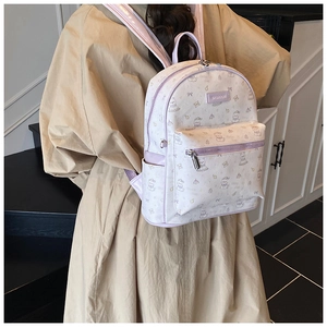 Détail d'un sac à dos scolaire lavande à fleurs porté sur un manteau long beige élégant