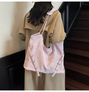 Side view of a large light pink shoulder tote bag with adjustable strap detail on model