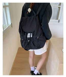 Detail of checkered nylon backpack featuring drawstring closure and brand label