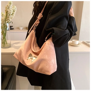 Pink tote bag detail with golden butterfly clasp and knotted strap on female model