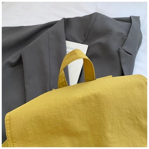 Detail of yellow canvas backpack with ripstop texture and top handle on casual blazer