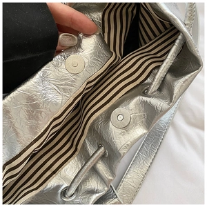 Détail du sac cabas plissé argenté avec fermoir magnétique et doublure rayée chic