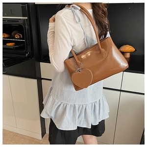 Dettaglio della borsa tote in pelle caramello lucida con ciondolo a cuore in cucina