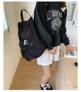 Side view of black checkered canvas backpack with drawstring closure on model
