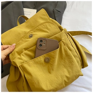 Detail of yellow nylon backpack front pocket showing storage capacity with a smartphone