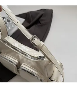 Close-up of premium silver hardware buckles and adjustable strap on a cream shoulder bag