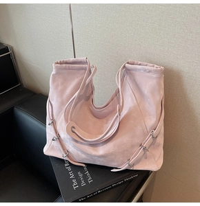 Artistic detail of pink vintage tote bag resting on black books in a soft interior setting
