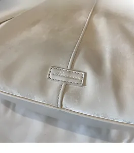 Gros plan du sac fourre-tout ivoire montrant le logo rectangulaire cousu et le cuir souple