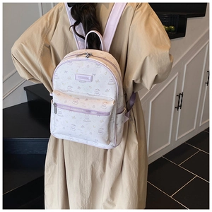 Gros plan d'un sac à dos d'écolier crème avec motifs d'ours et bretelles mauves sur un mannequin