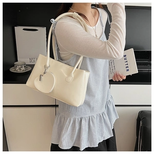 Dettaglio di una borsa a spalla avorio con ciondolo a forma di cuore e finitura lucida