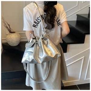 Détail d'un sac seau métallisé argenté avec texture plissée et cordon de serrage chic