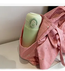 Detailed side view of a pink canvas tote showing a side pocket holding a water bottle