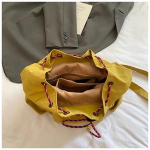 Top-down view of yellow canvas drawstring backpack showing brown lining and inner pockets