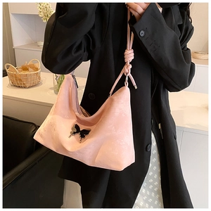 Detail of light pink suede tote bag with black butterfly metal buckle and knotted strap