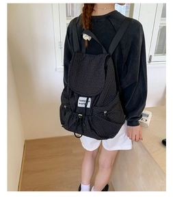 Detail of checkered backpack with drawstring closure and brand label shown on model