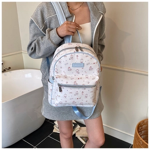 Détail d'un sac à dos blanc et bleu élégant avec imprimé chat et logo de marque