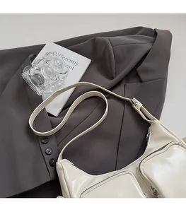Detail of minimalist cream leather shoulder bag featuring functional dual zip front pockets