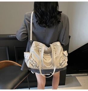 Detailed back view of model wearing cream oversized tote bag with biker buckle accents