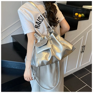 Sac seau plissé argenté avec pochette porté par un mannequin à l'épaule pour femme