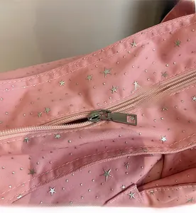 Close-up of smooth nylon zipper and silver star pattern on pink canvas tote bag