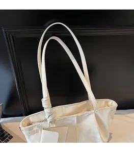 Détail d'un sac cabas crème avec des bretelles nouées élégantes et une texture plissée