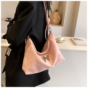 Detailed view of pink suede hobo bag with butterfly buckle and knotted shoulder strap