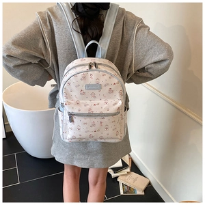 Détail du sac à dos crème avec bordure bleue et motifs d'ours porté par un modèle