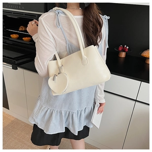 Borsa a spalla in pelle bianco crema con ciondolo a cuore in un ambiente da cucina
