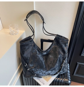 Close-up of vintage black distressed leather tote bag with adjustable strap and side buckle