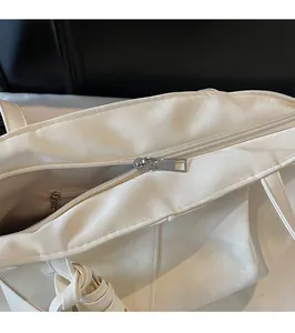 Détail du sac cabas blanc montrant la fermeture éclair en métal et la poche intérieure