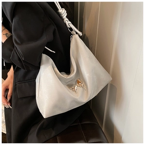 Close-up of metallic silver tote bag with knot strap and silver butterfly ornament
