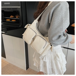 Detail view of cream white multi-pocket shoulder bag in glossy PU with utilitarian design