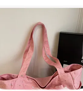 Detail of pink canvas tote bag featuring silver star patterns and wide shoulder straps