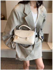 Borsa a tracolla in pelle bianca con trama litchi indossata con un blazer grigio chic