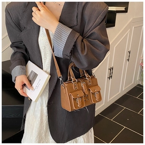 Brown biker-style bag with double front pockets and metal buckles shown with a model