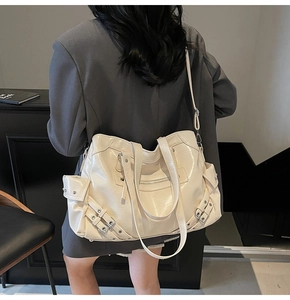Détail du grand sac fourre-tout crème avec poches zippées multiples et clous en métal