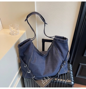 Detailed view of dark blue denim tote bag with contrast stitching and silver hardware buckles