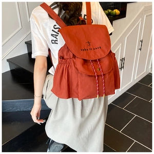 Détail d'un sac à dos en toile orange avec texte brodé et fermeture à cordon
