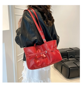 Vue latérale du sac porté épaule rouge avec boucles argentées et œillets sur modèle