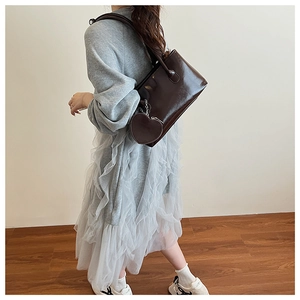 Dettaglio borsa shopper in pelle verniciata marrone scuro con ciondolo a cuore chic